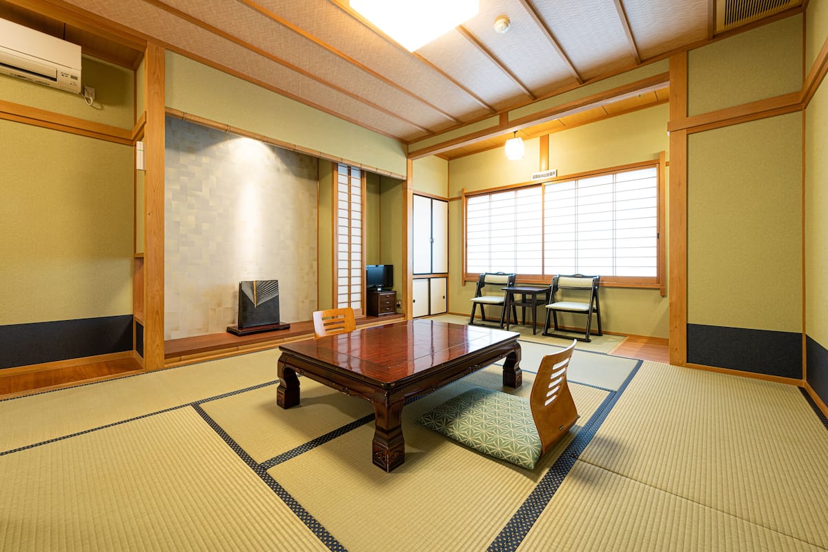 Um quarto japonês tradicional, com piso de tatame, uma mesa de madeira e portas deslizantes.