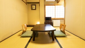A tatami mat room with a low table and two wooden chairs. - Yamadaya Ryokan (Kyoto)
