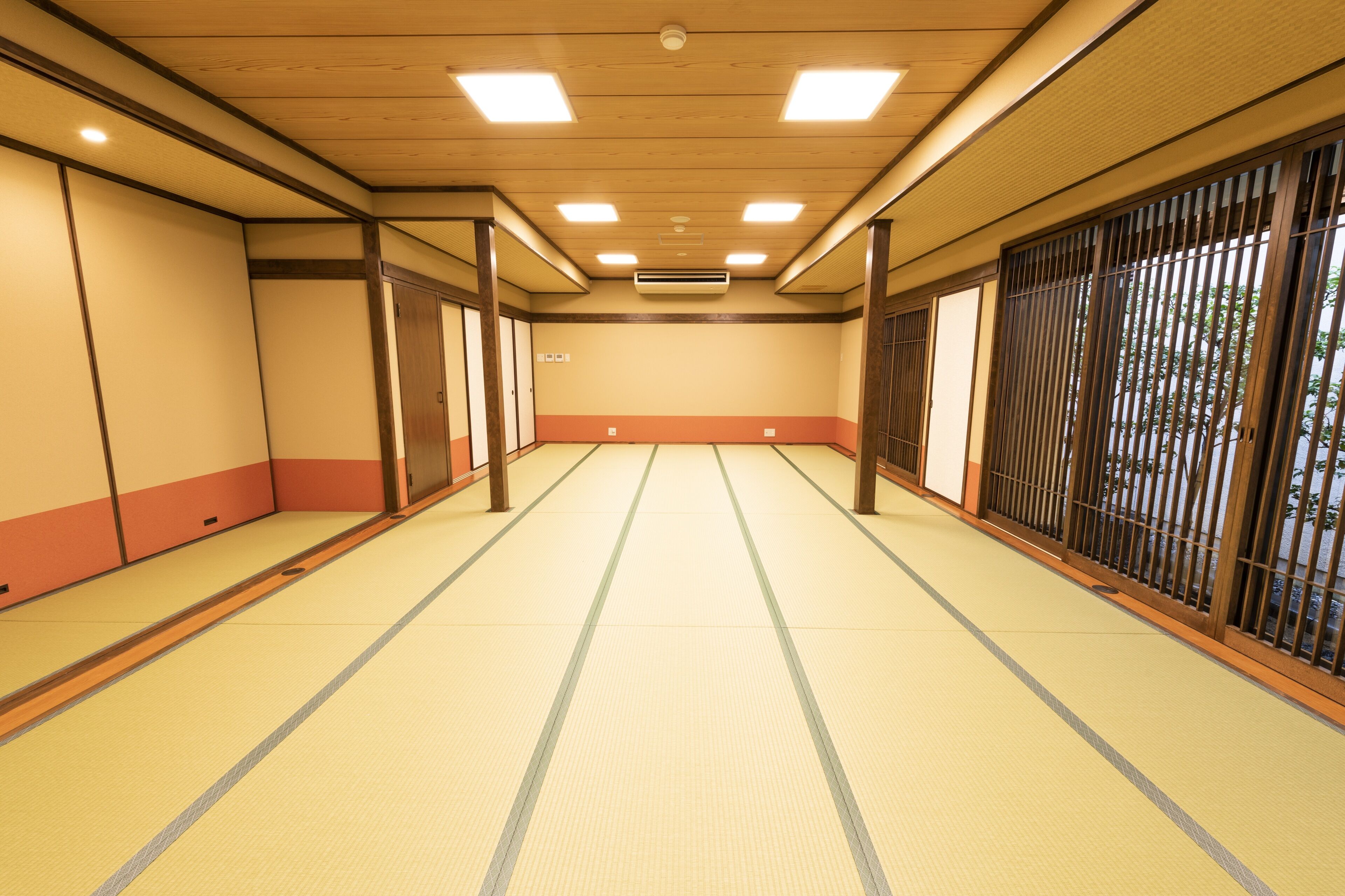 A traditional Japanese room with tatami flooring, sliding doors, and a view through a shoji screen.