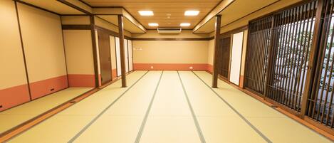 A traditional Japanese room with tatami flooring, sliding doors, and a view through a shoji screen.