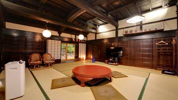 Una habitación japonesa tradicional con suelo de tatami, un futón en el centro, un televisor y muebles de madera.