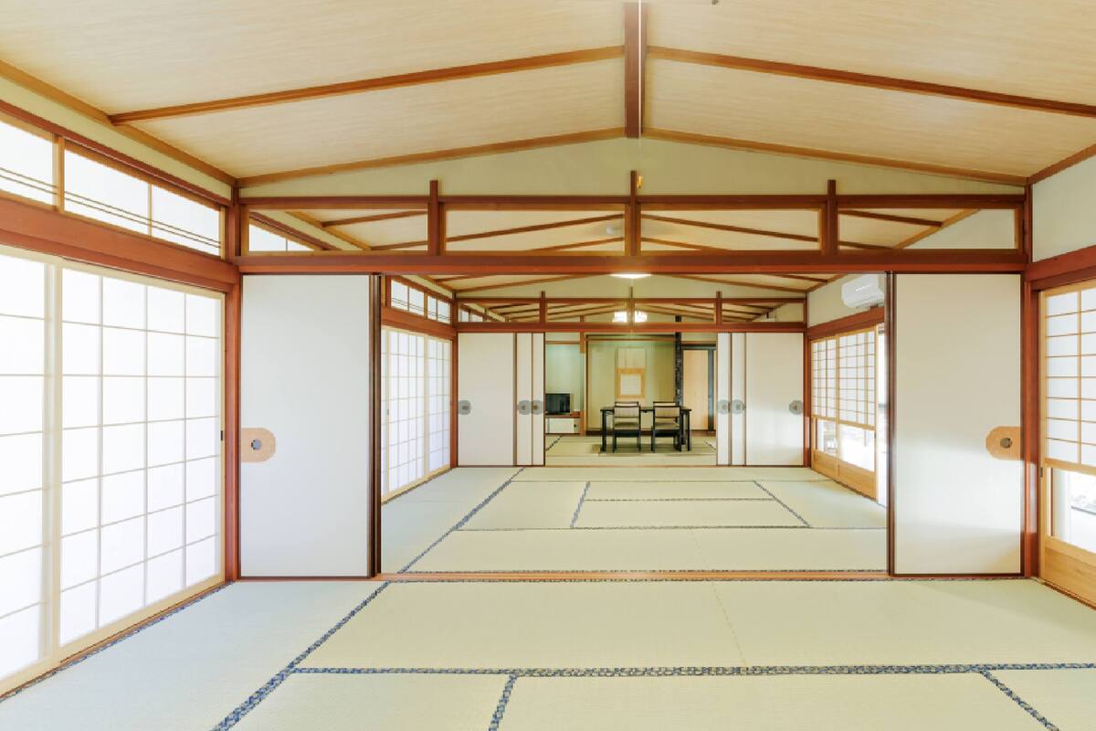 Una habitación japonesa tradicional con suelo de tatami, puertas correderas y estructura de techo de madera.