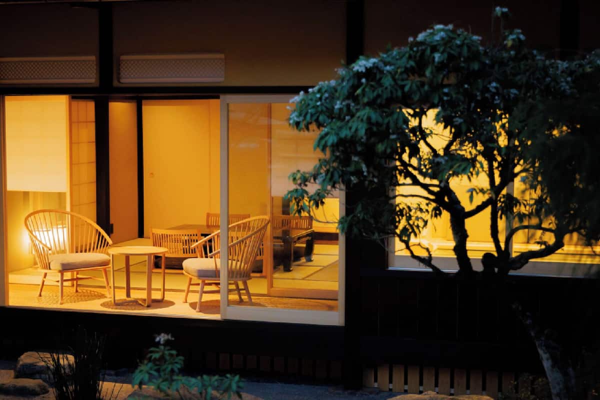 Una habitación tradicional japonesa con suelo de tatami, mesas bajas y sillas.