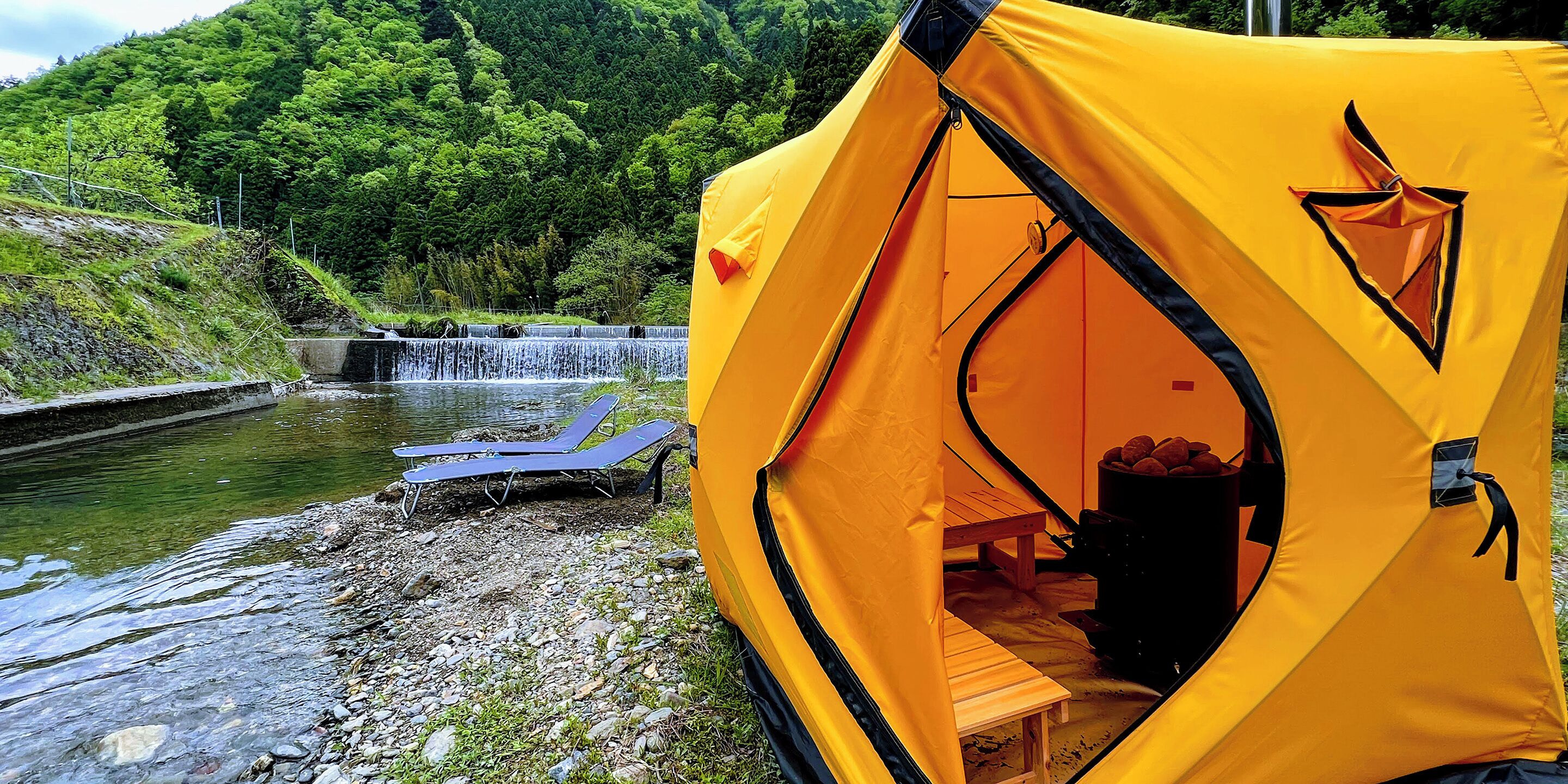 A yellow tent with a waterfall in the background.