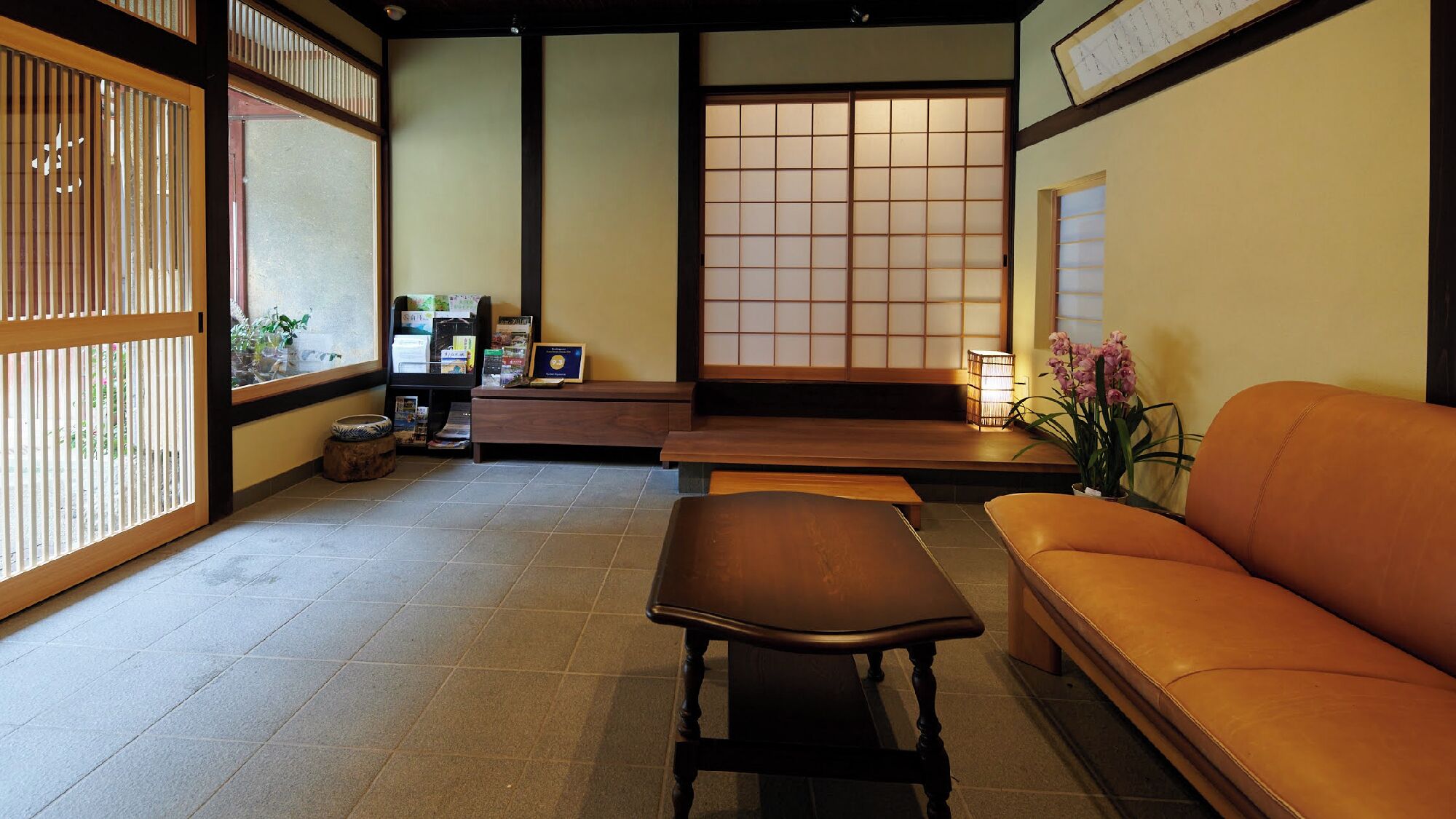 A traditional Japanese room with tatami flooring, a low table, a sofa, and a shoji screen door.