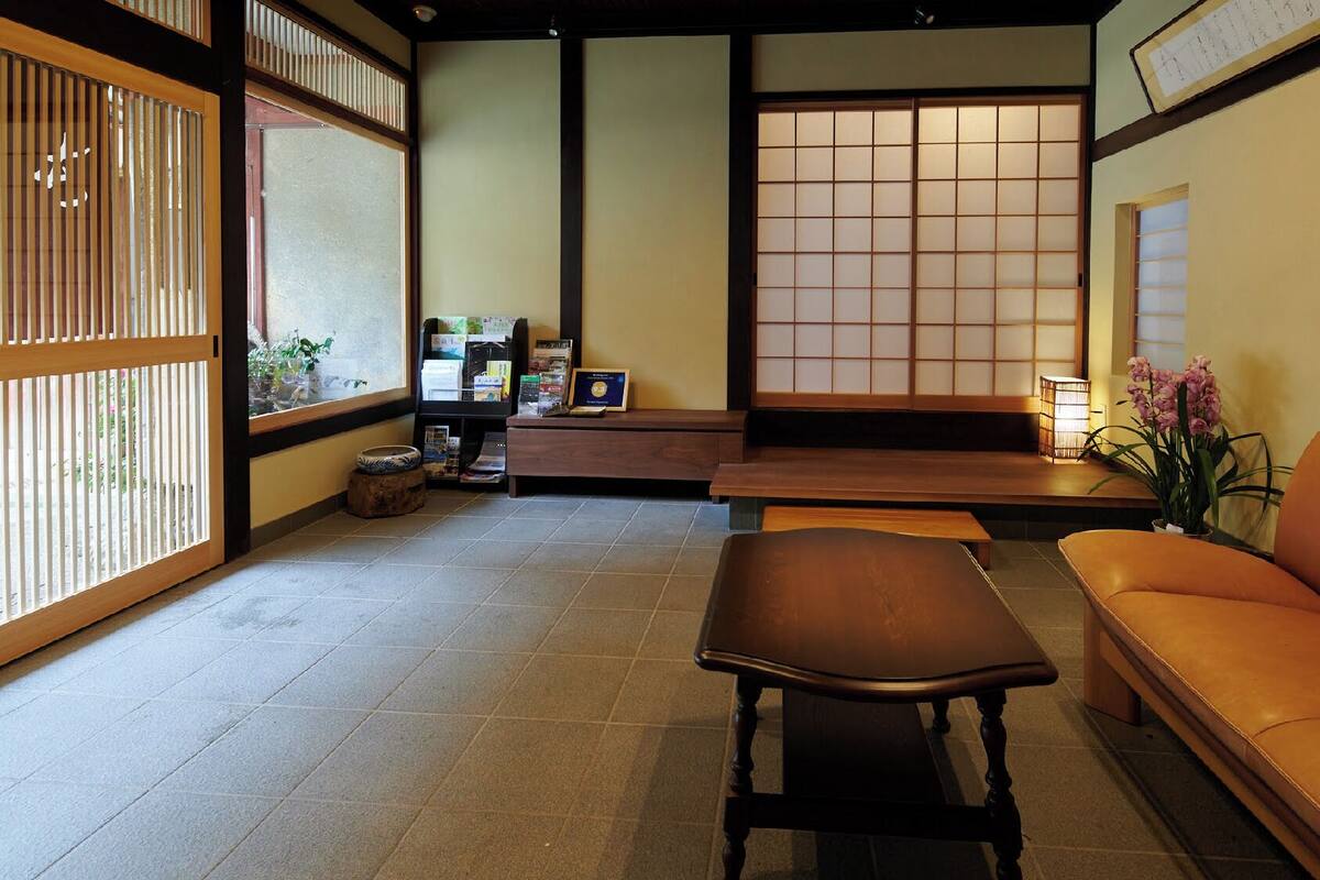 Una habitación japonesa tradicional con suelo de tatami, una mesa baja, un sofá y una puerta corredera de shoji.
