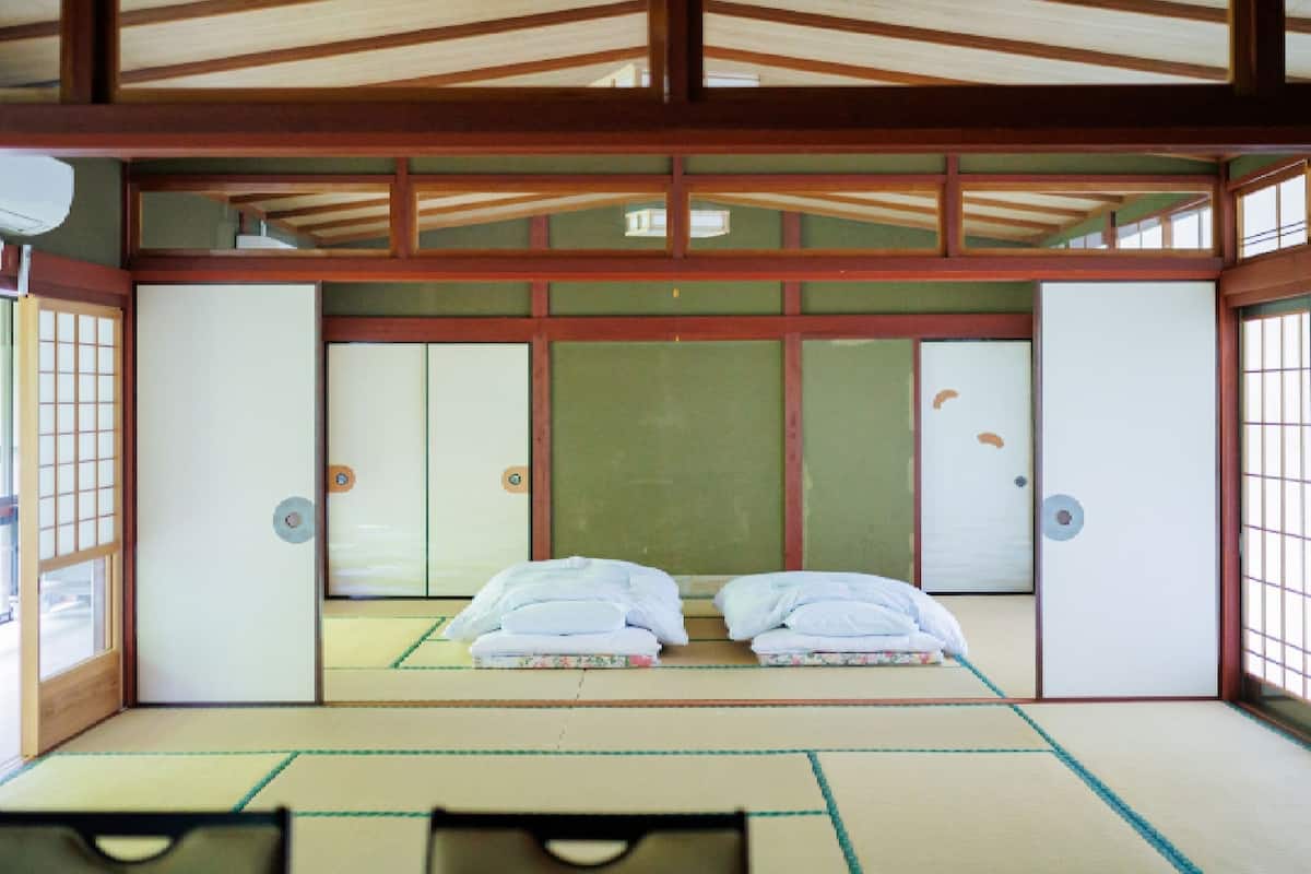 Una habitación japonesa tradicional con suelo de tatami, puertas correderas y una cama con almohadillas.