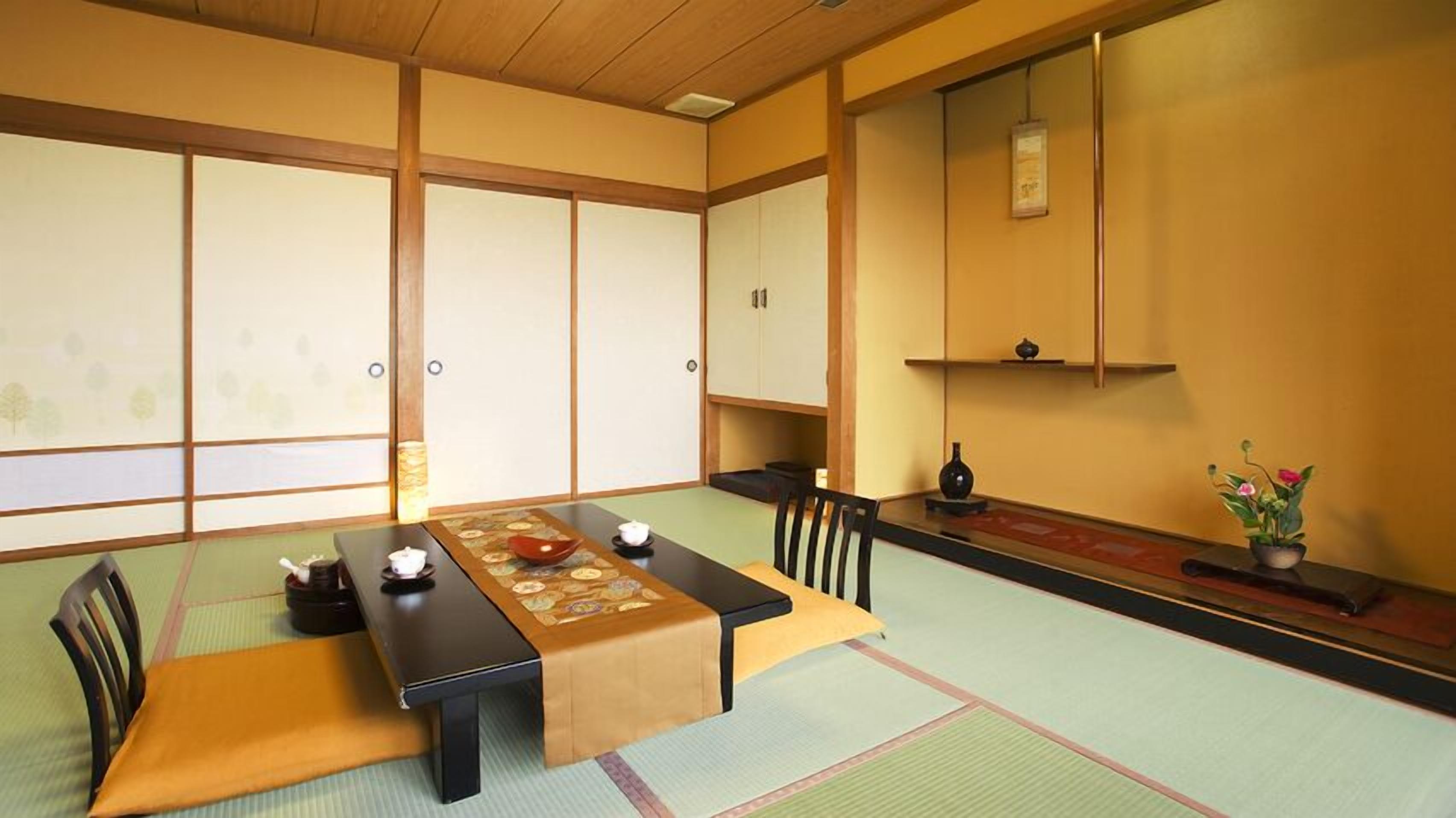 Een traditionele Japanse kamer met tatami vloeren, een lage tafel met kussens en schuifdeuren.