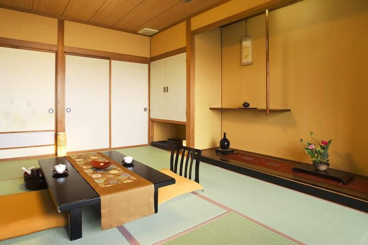 A traditional Japanese room with tatami flooring, a low table with cushions, and sliding doors.