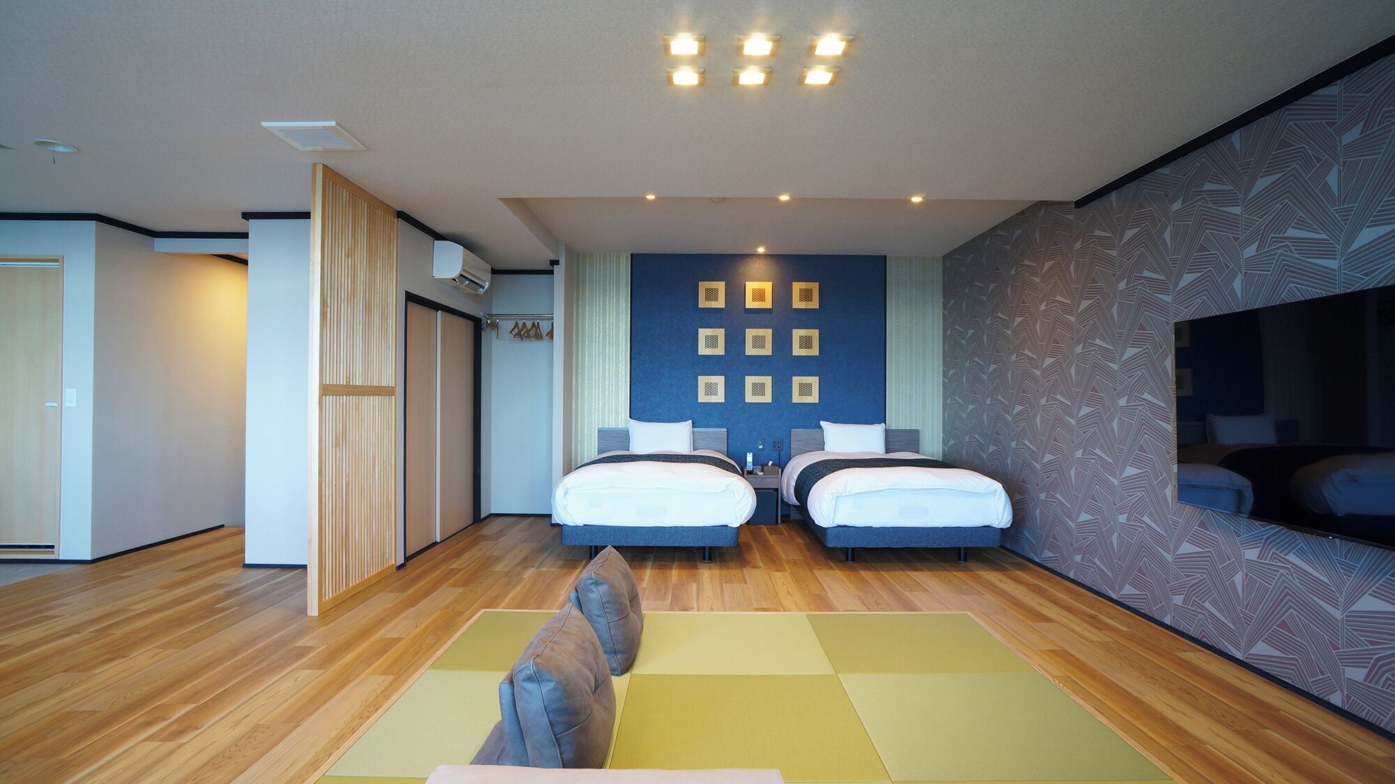 Een moderne hotelkamer met twee bedden, een grote spiegel en een houten vloer.