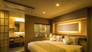 A hotel room with a large bed, a bedside table, a mirror, and a window with blinds.