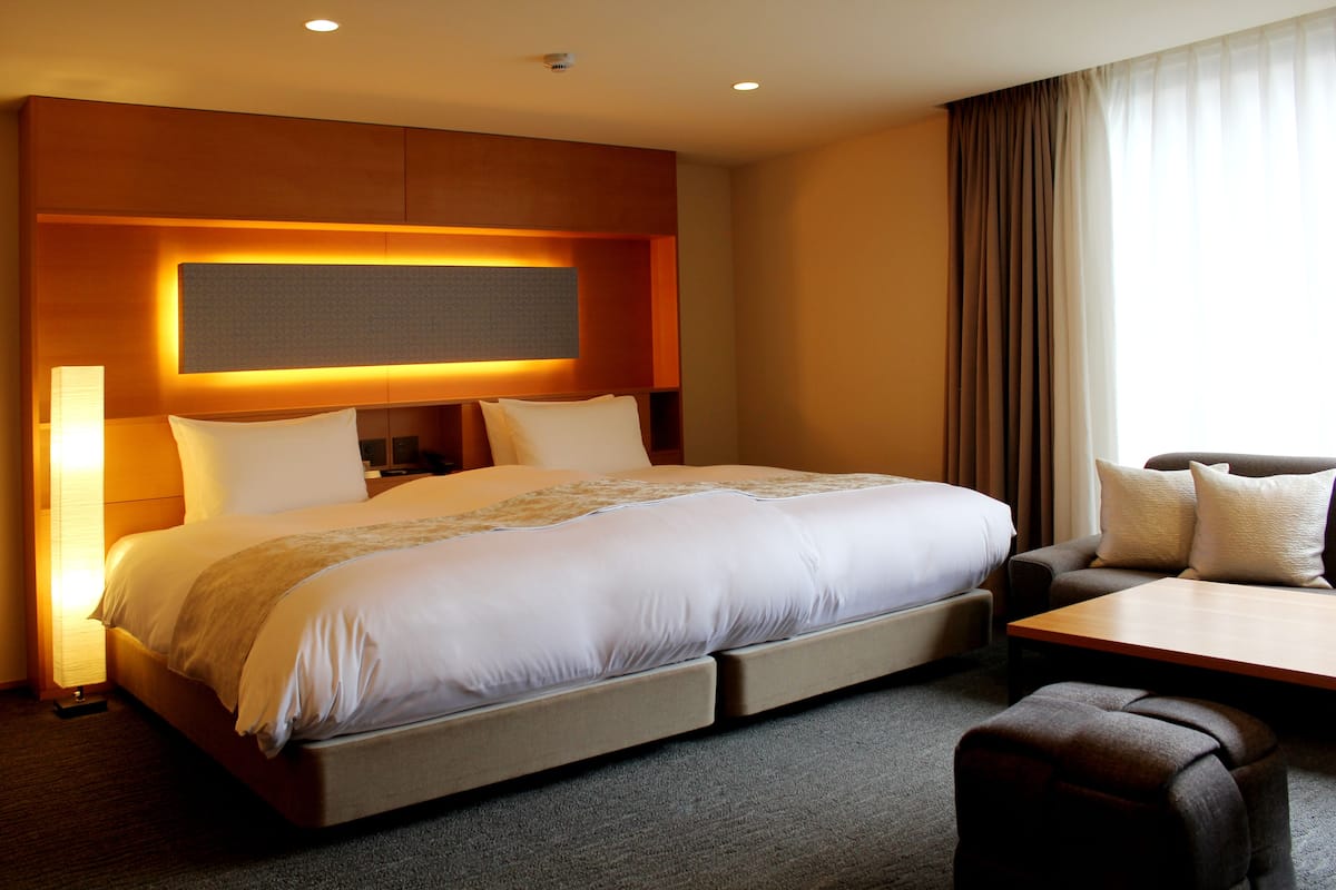A hotel room with a large bed, a desk, and a sofa.