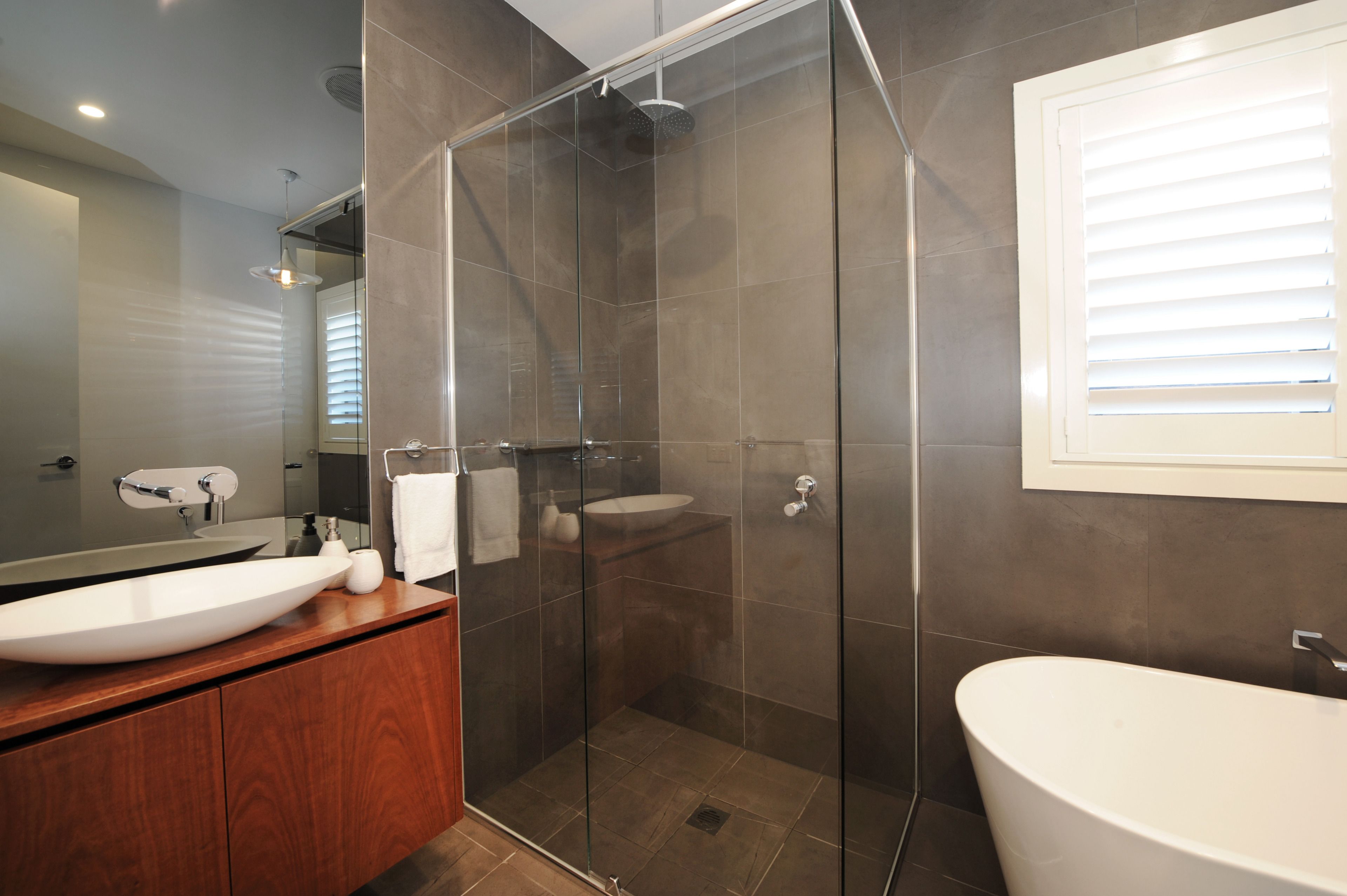 A modern bathroom with a glass-enclosed shower, a freestanding bathtub, and a vanity with a large sink.
