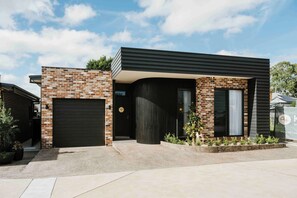 A modern two-story house with a brick facade, a dark garage door, and a landscaped front yard. - Kirsten Accommodation Mudgee (Mudgee)