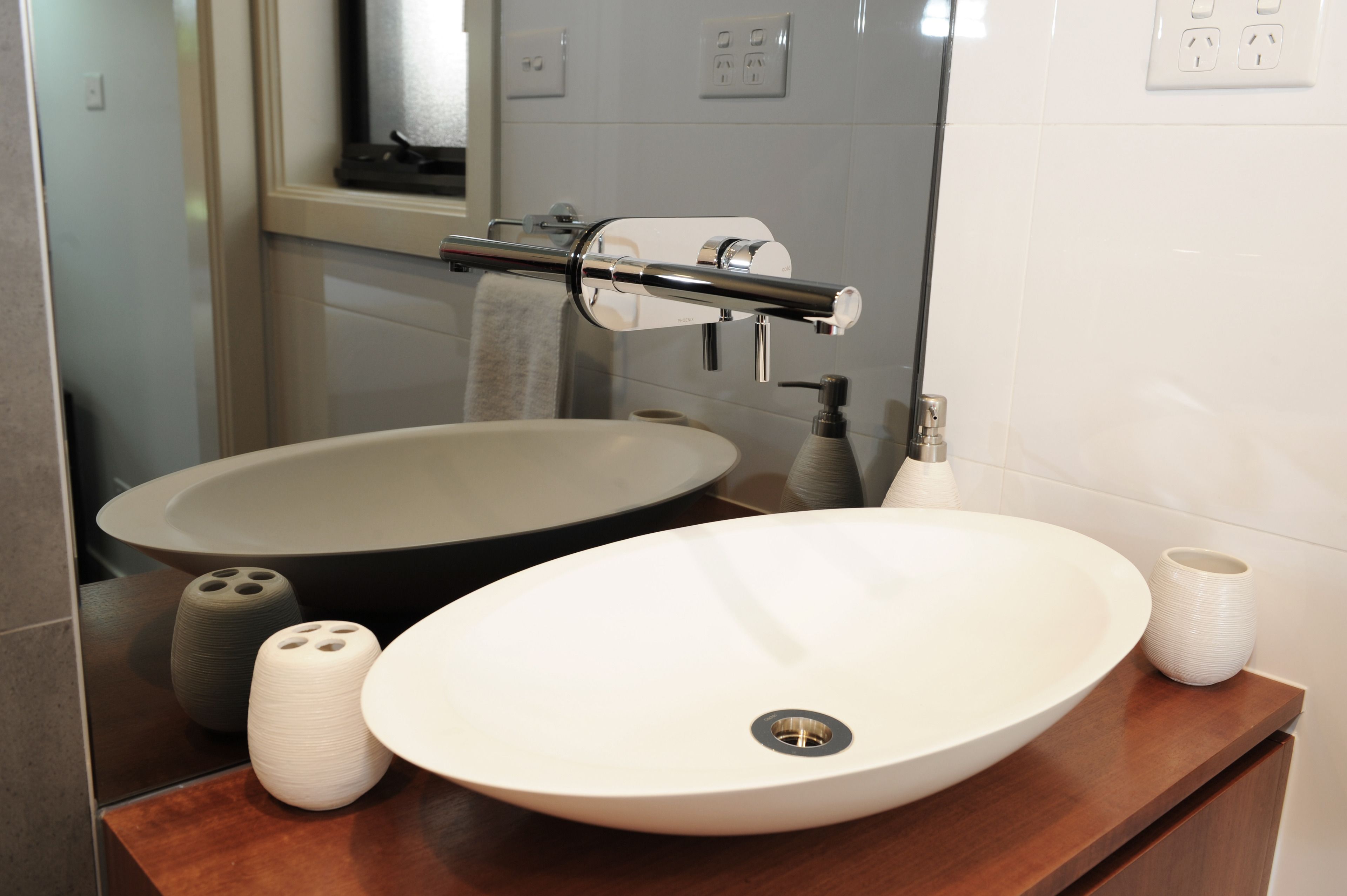Un baño con un lavamanos ovalado grande, un espejo y un perchero para toallas.