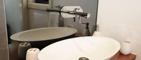 A bathroom with a large oval sink, a mirror, and a towel rack.