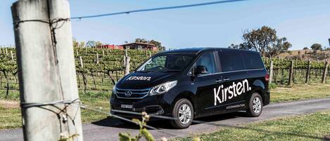 Una minivan negra con la marca 'Kirsten' estacionada en una carretera rural.