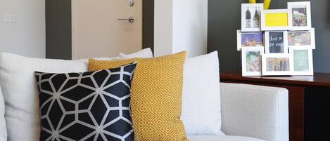 A modern living room with a white sofa, a geometric patterned pillow, and a yellow patterned pillow.