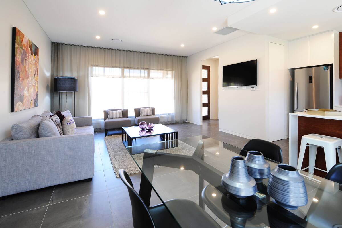 A modern living room with a sofa, coffee table, and glass dining table.