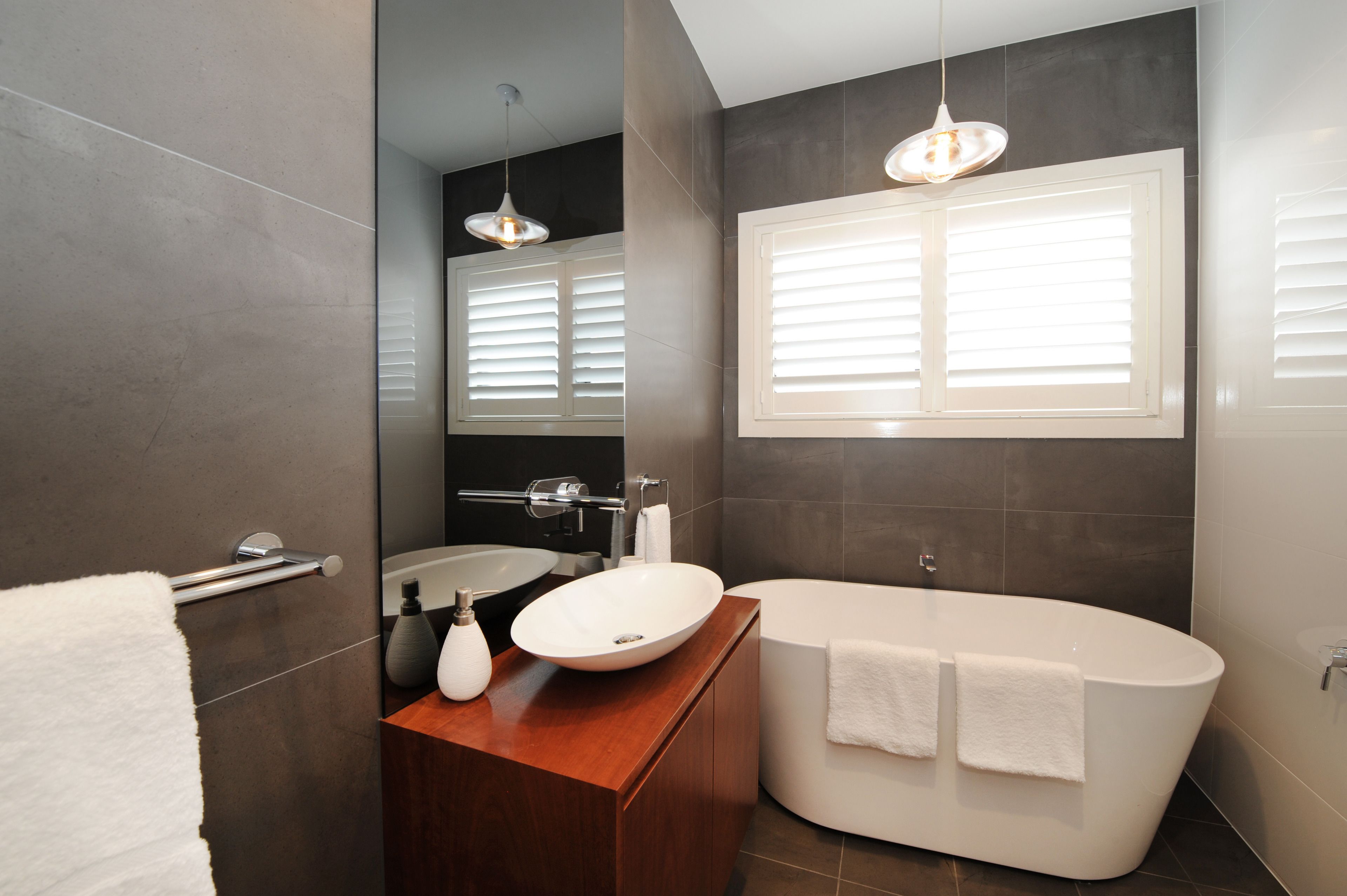 A modern bathroom with a freestanding bathtub, a large mirror, and a vanity with a sink.