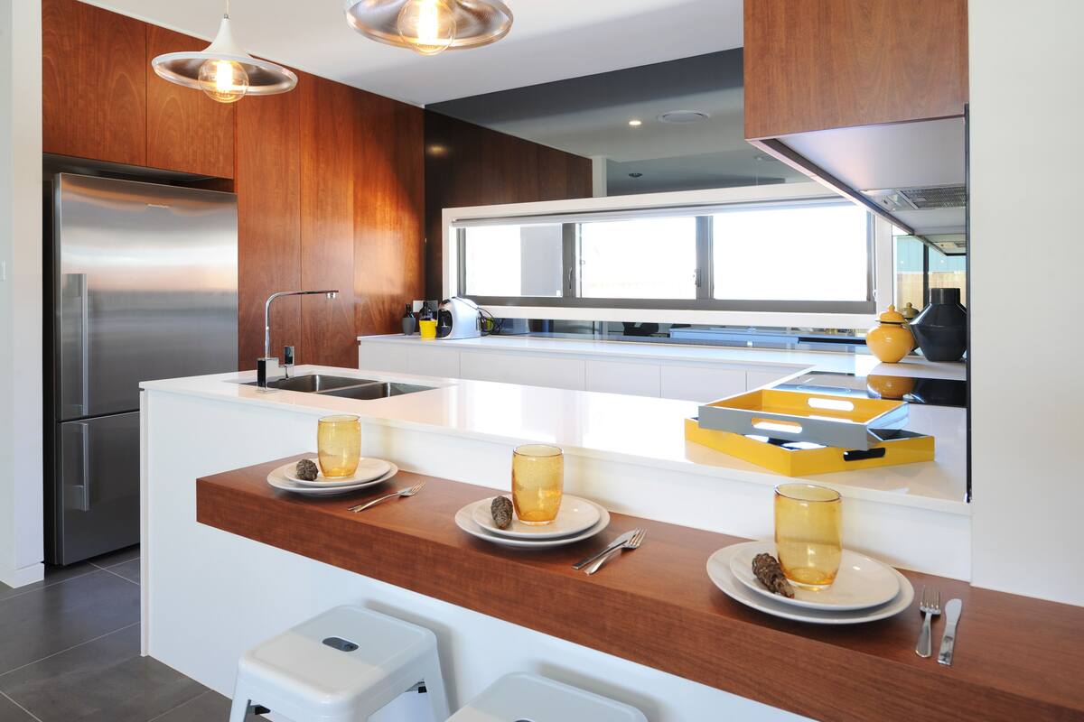A modern kitchen with a central island, stainless steel appliances, and a large window providing natural light.