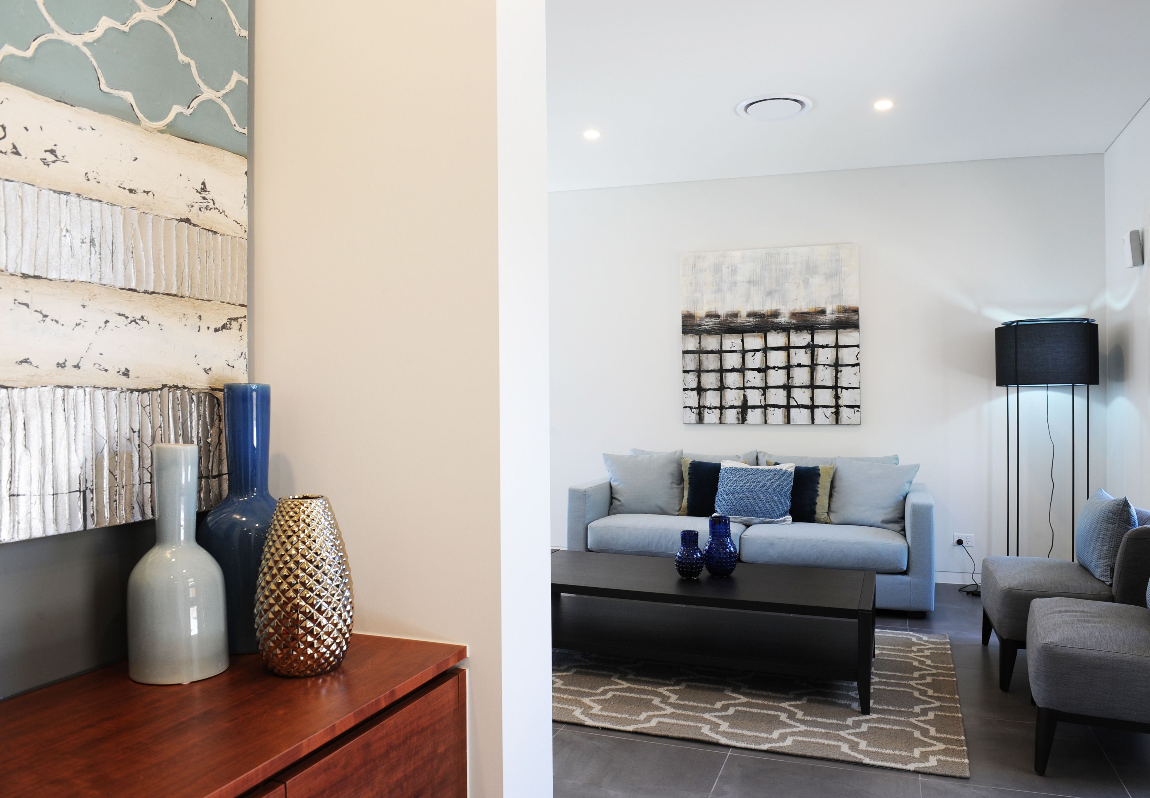 Una sala de estar moderna con sofá, mesa de centro y jarrones decorativos.
