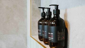 Three bottles of 'Basil + Lime' conditioner on a shelf.