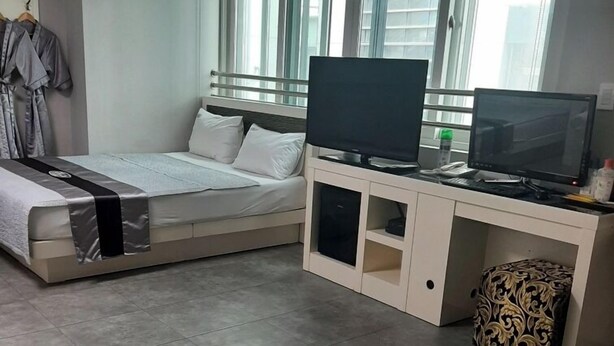Un dormitorio moderno con cama, televisor y escritorio.
