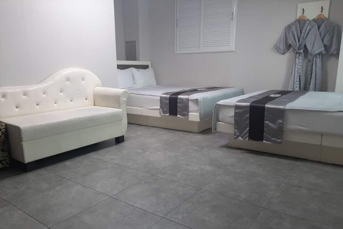 A hotel room with two beds, a sofa, and a wardrobe.