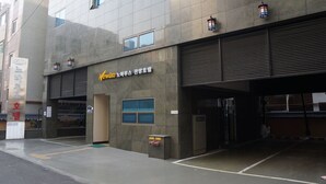 Un edificio moderno con un letrero en coreano, un hidrante y una puerta de garaje cerrada.