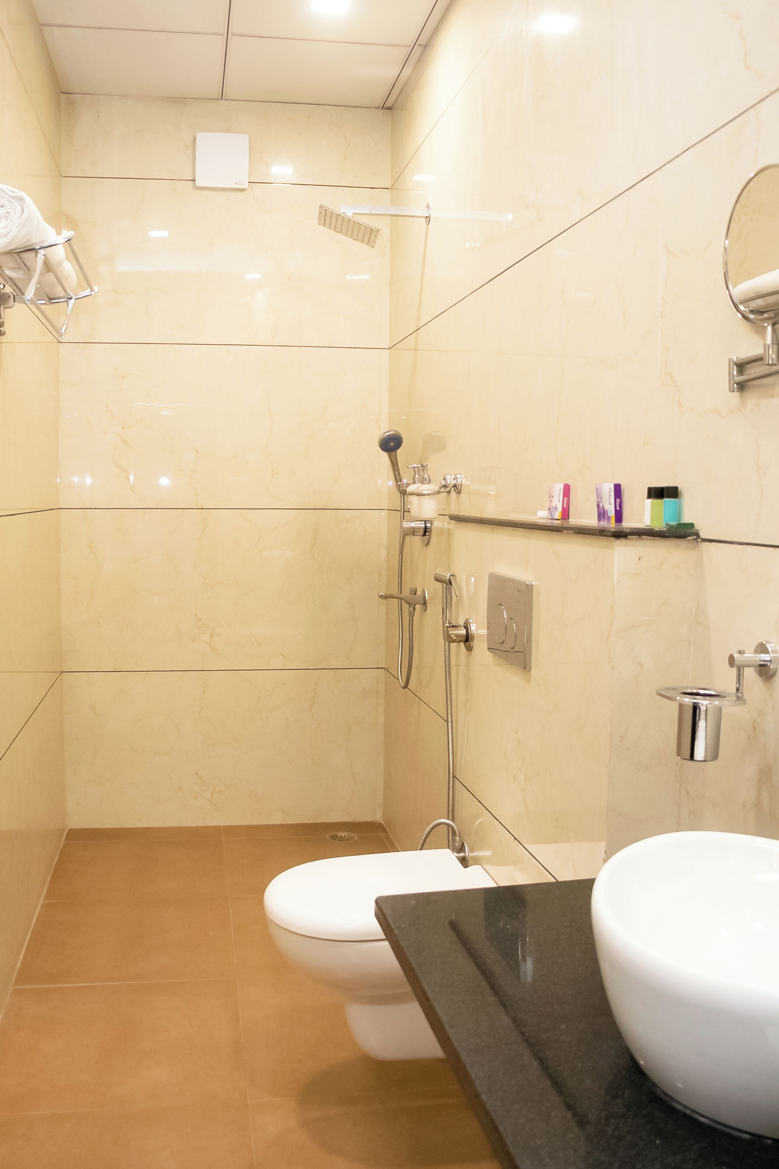 A bathroom with a toilet, a sink, a shower, and a mirror.