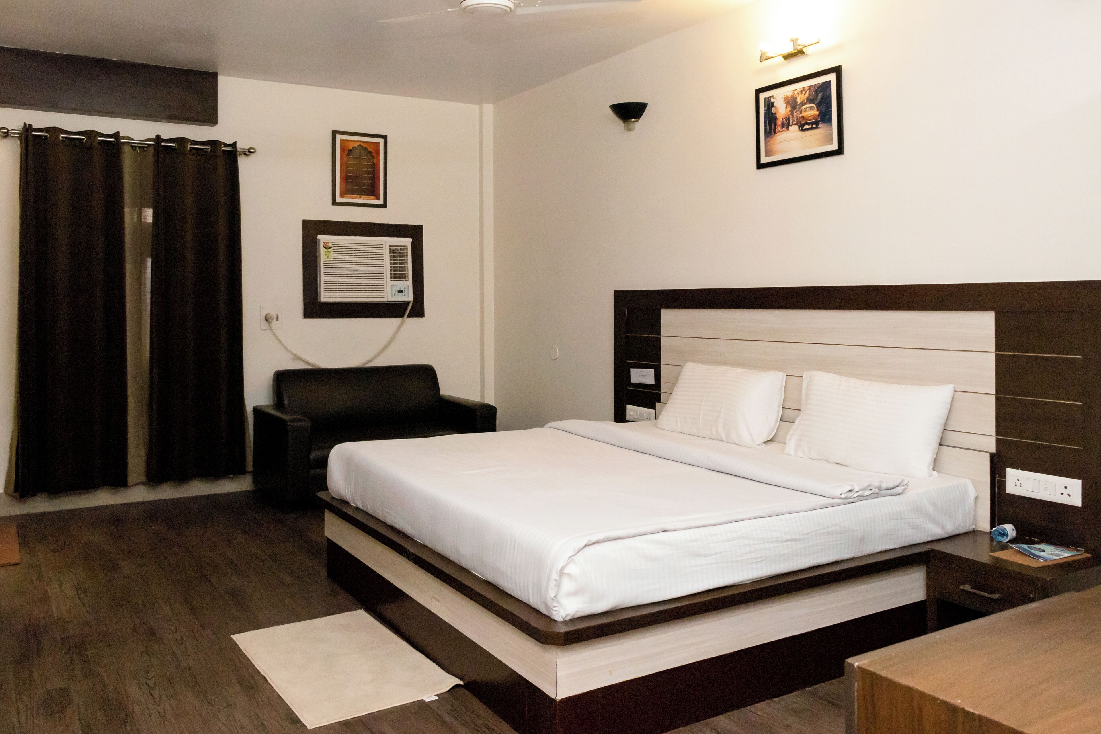 Une chambre d’hôtel équipée d’un lit, d’une chaise, d’un bureau et d’un climatiseur fixé au mur.