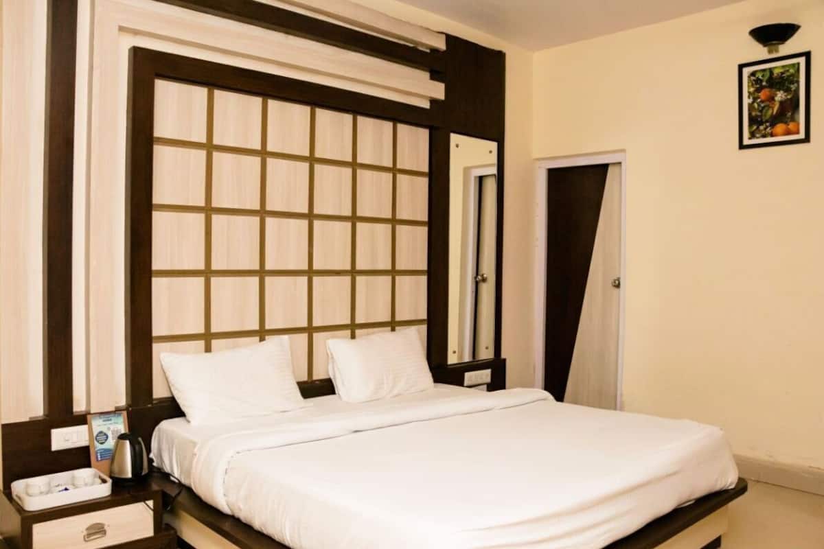 Ein Hotelzimmer mit einem Bett, einem Nachttisch mit Tassen und einem Bilderrahmen an der Wand sowie einer Tür.
