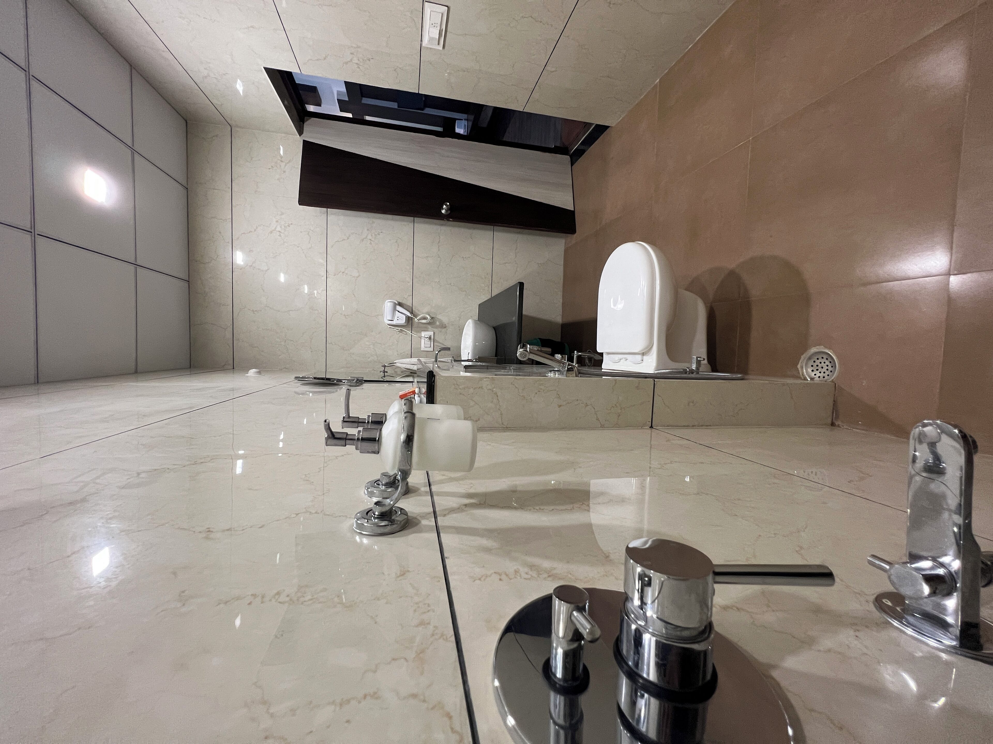 A modern bathroom with a large mirror, a toilet, a sink, and a shower area.