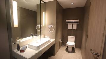 Un baño moderno con un espejo grande, un lavabo blanco, un inodoro y una zona de ducha.