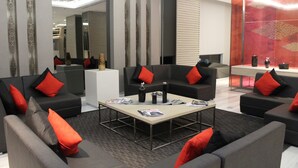 Et moderne loungeområde med sofaer og et sofabord, med røde og grå puder.