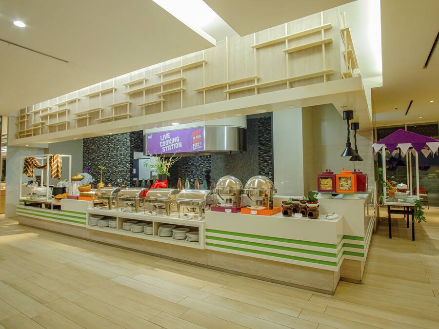 A buffet area with multiple serving stations, a live cooking station, and a seating area with a table and chairs.