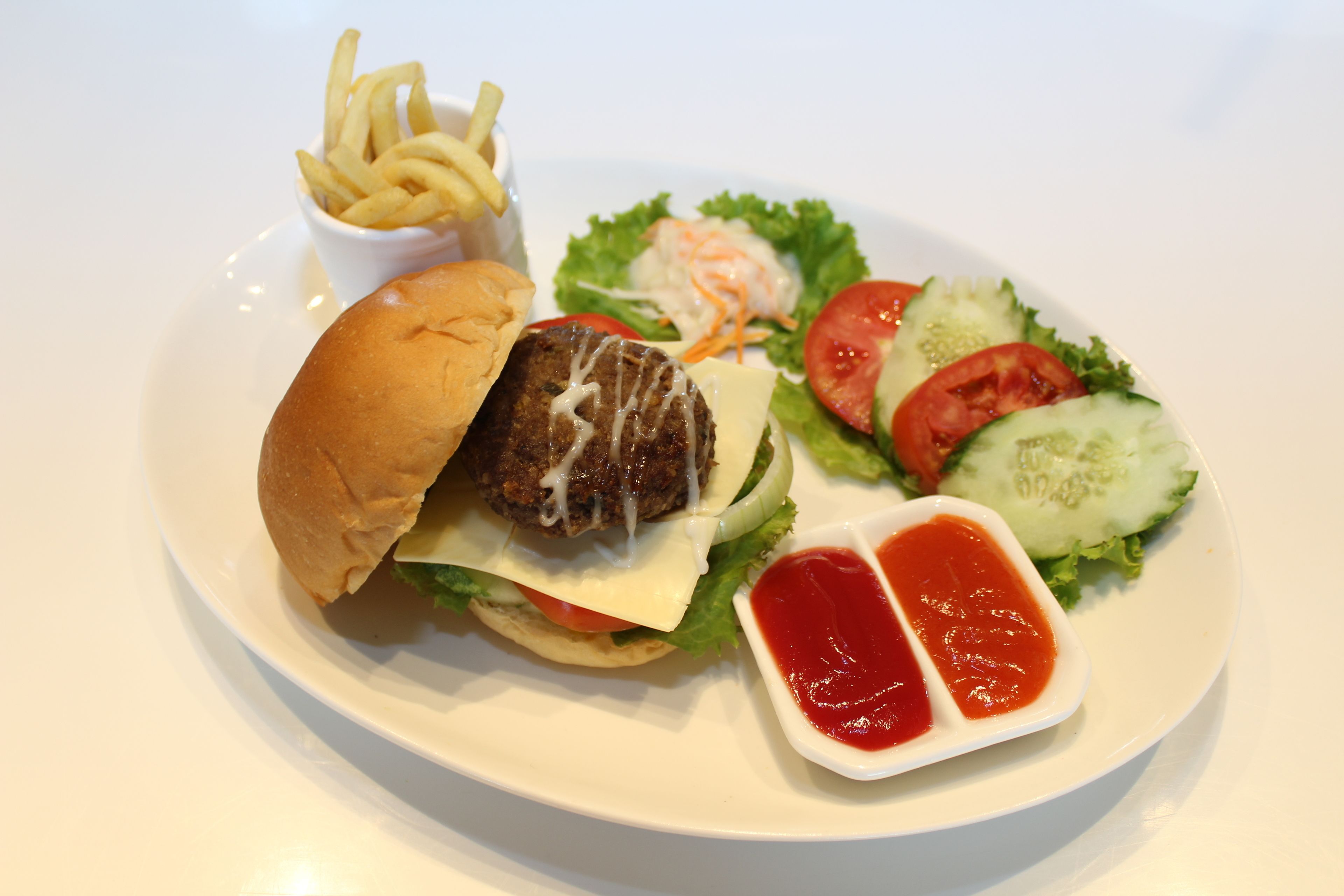 A plate with a burger, fries, salad, and ketchup.