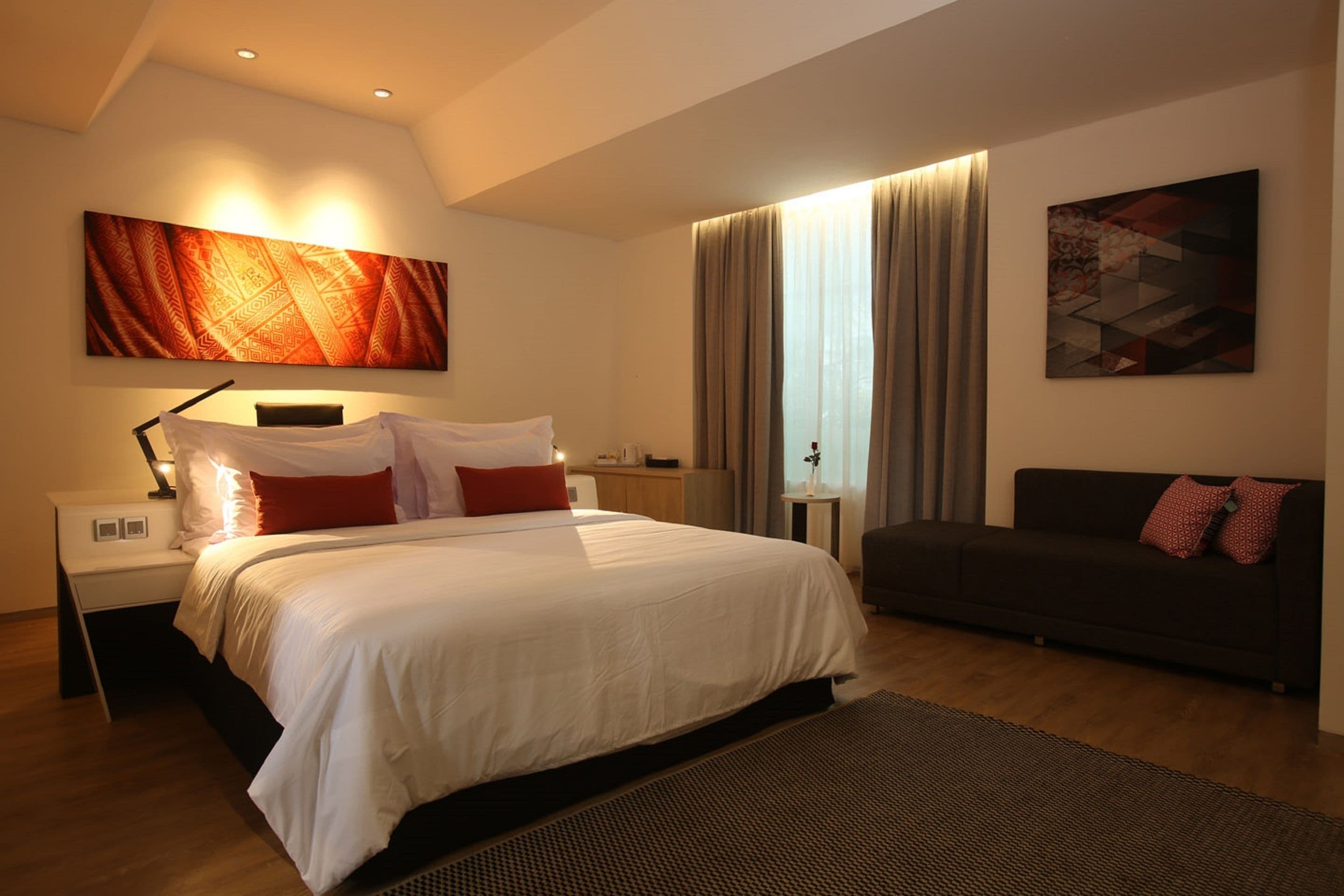Une chambre moderne avec un grand lit, un canapé et des œuvres d’art accrochées aux murs.