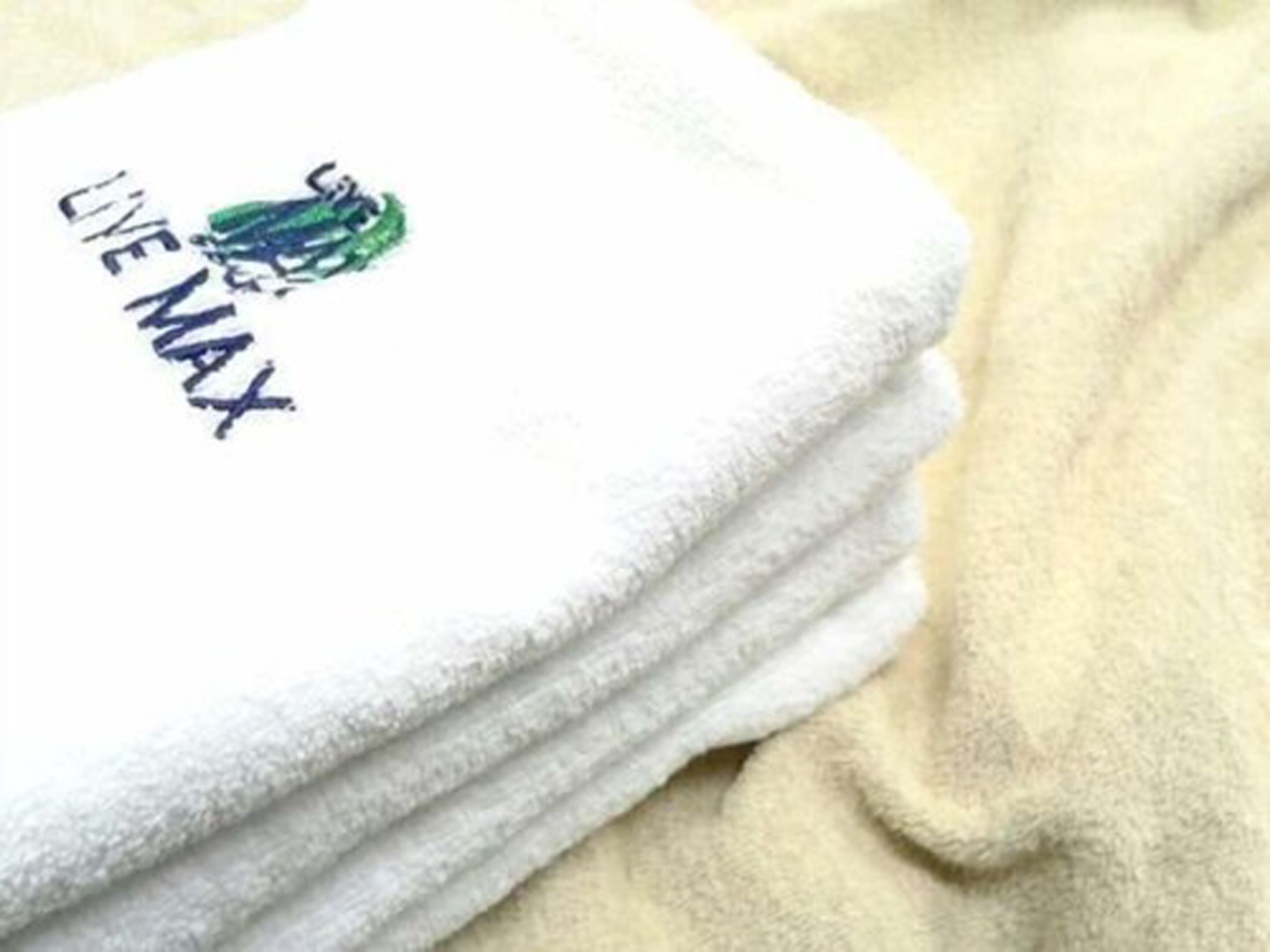 A stack of white towels with a logo and text on one of them.