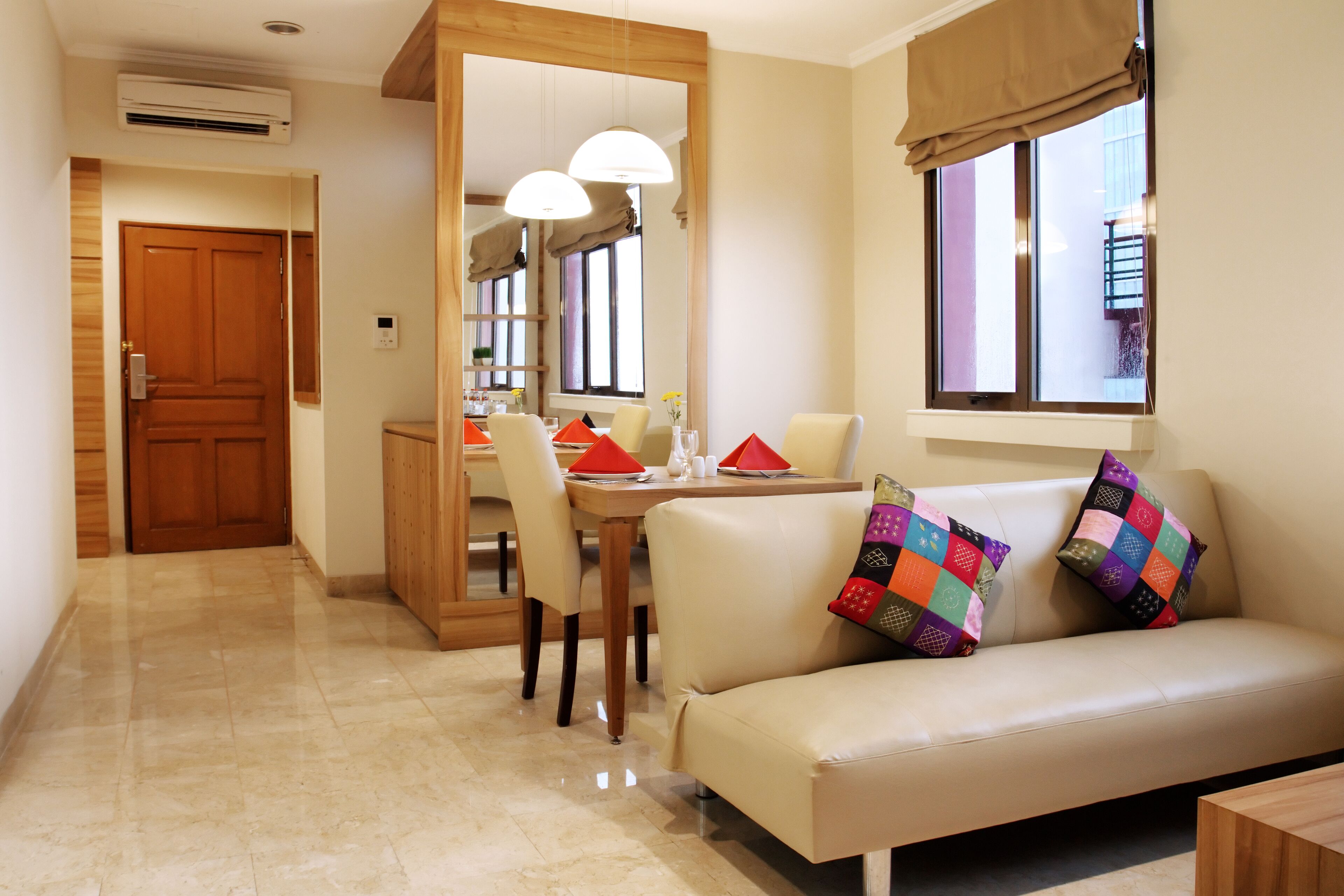 A modern living room with a sofa, a dining table with chairs, and a window with curtains.