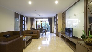 Ein modernes Wohnzimmer mit Sofa, Couchtisch und TV-Schrank. Ein Balkon bietet Blick auf Grünflächen.