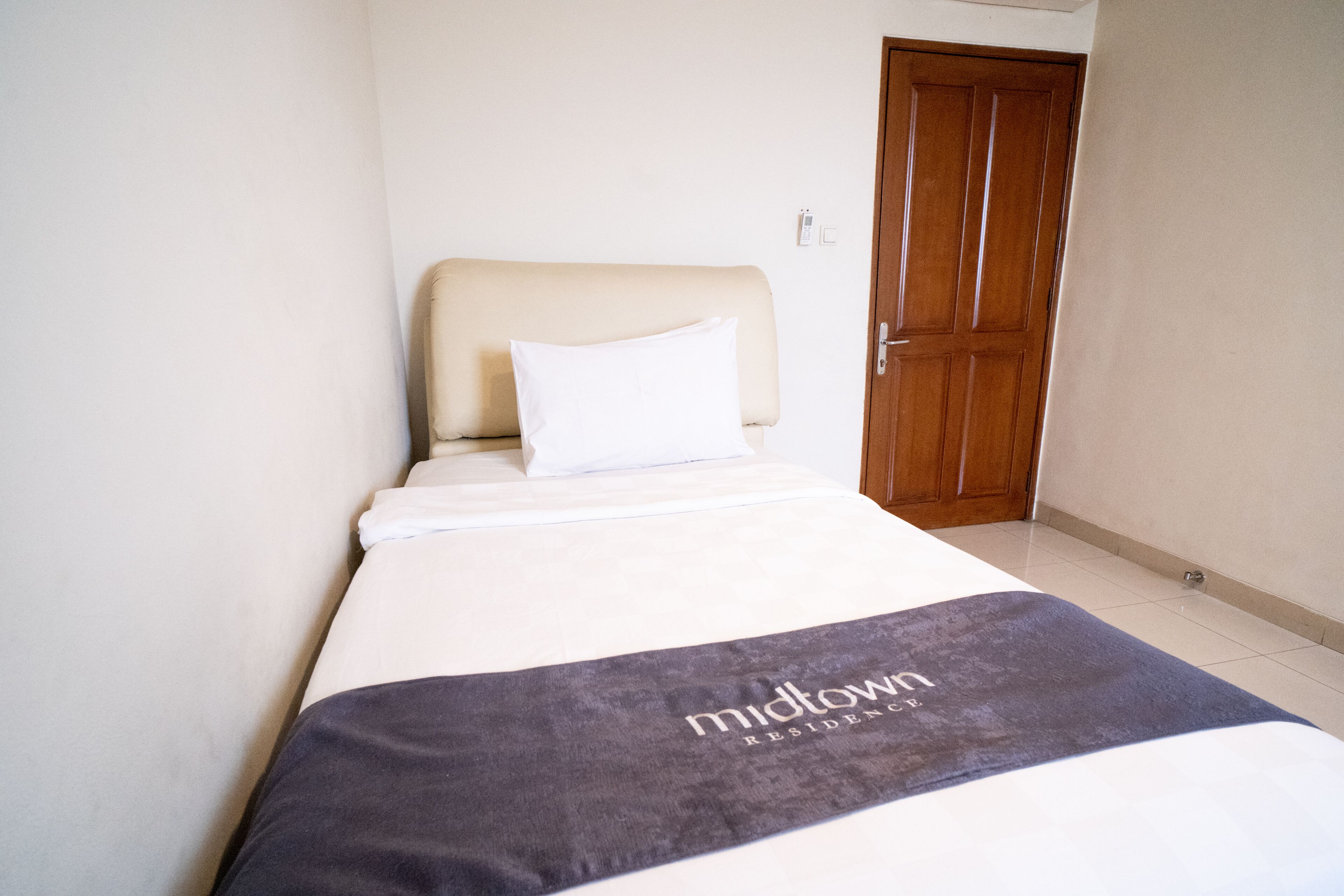 Una habitació d'hotel amb un llit, una porta de fusta i una paret blanca.