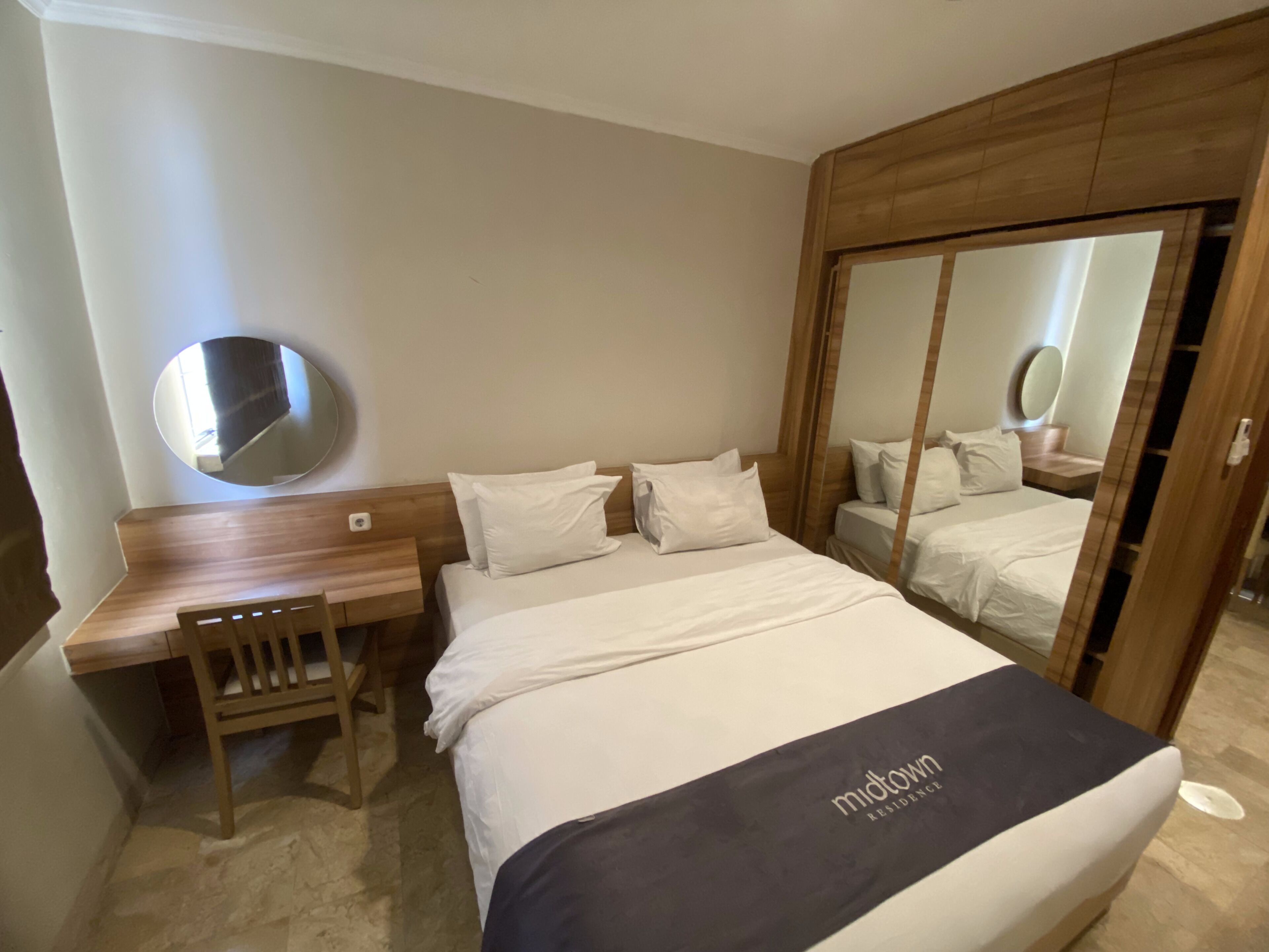 Een hotelkamer met een bed, een bureau, een stoel, een spiegel en een kledingkast.