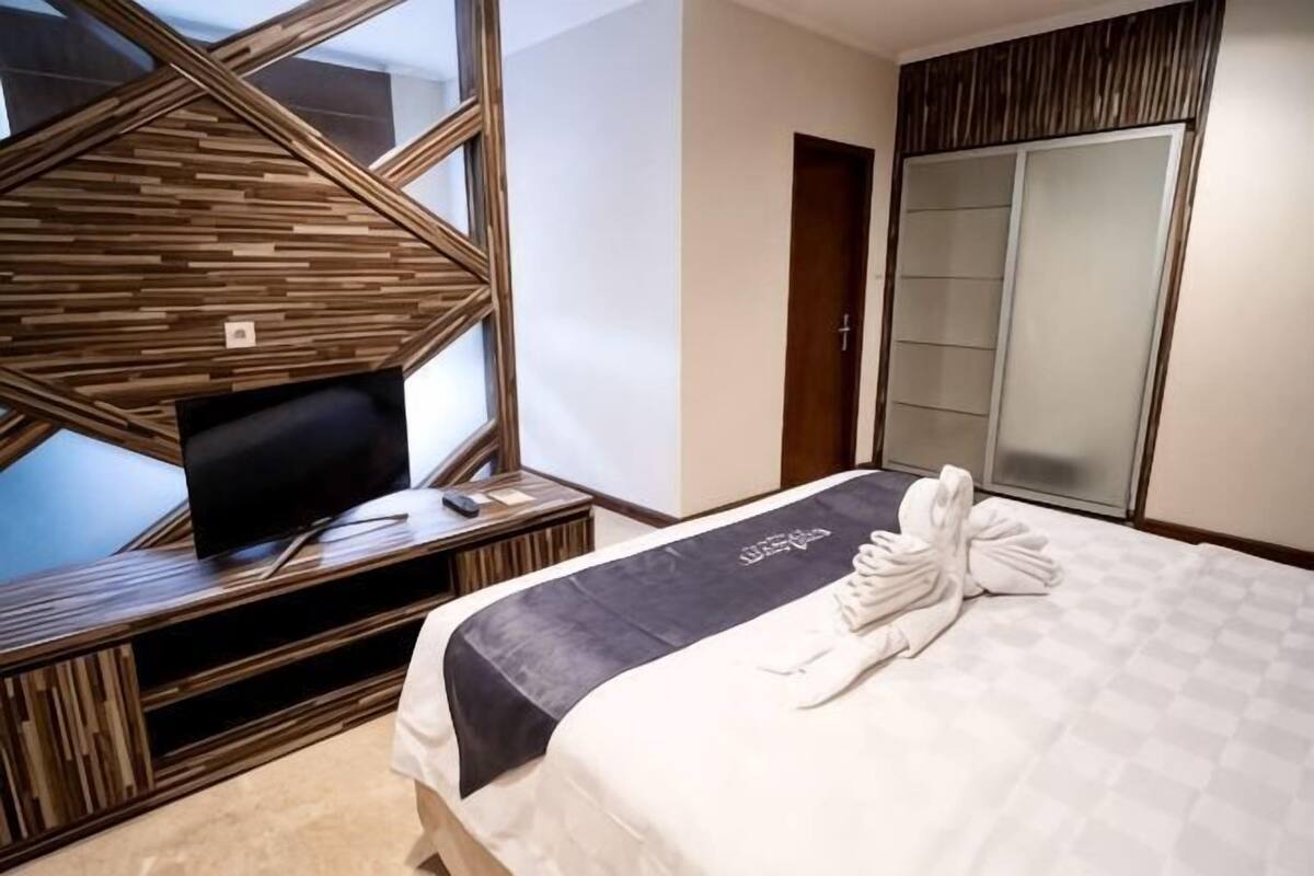 Een hotelkamer met een bed, een televisie, een kledingkast en een groot raam.