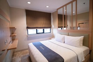 Een hotelkamer met een bed, een raam met uitzicht, een spiegel en een plank.