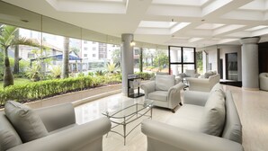 Eine moderne Hotelhalle mit einem Glastisch, weißen Sofas und Blick auf den Garten.