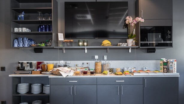 A modern kitchen with a flat-screen TV, a microwave, and various food items on the counter. - Hotell Leksand (Leksand)