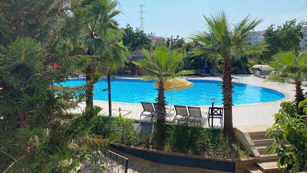 A pool area with palm trees, lounge chairs, and a clear blue pool. - Lemas Suite Hotel  (Manavgat)