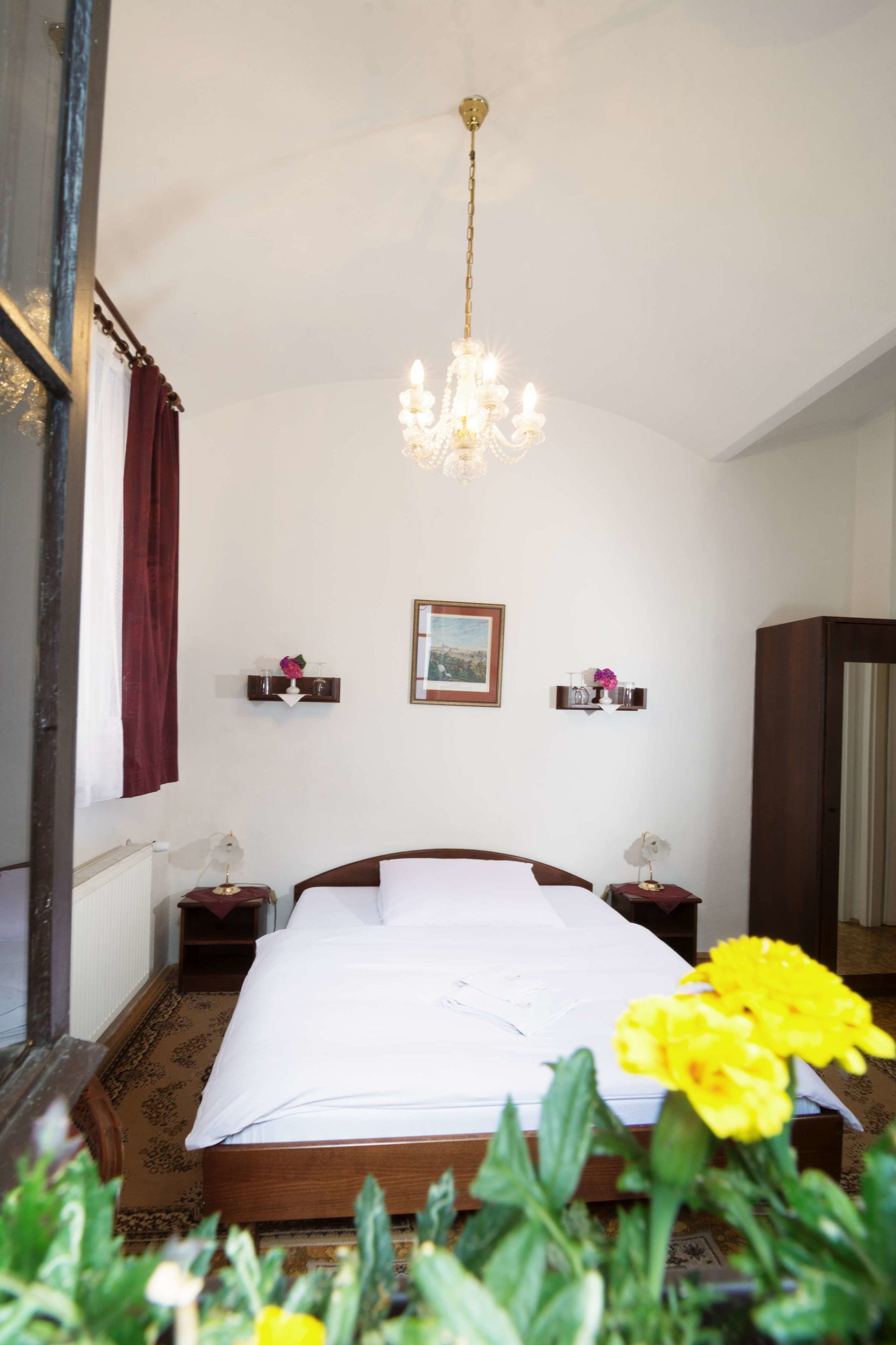 Une chambre à coucher avec un grand lit, un lustre, des tables de chevet et un miroir.